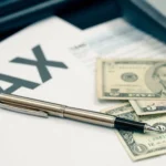 A professional desk setup featuring a calculator, a pen, and US dollar bills resting on a 1040 tax form, representing strategic planning for small business tax loopholes.
