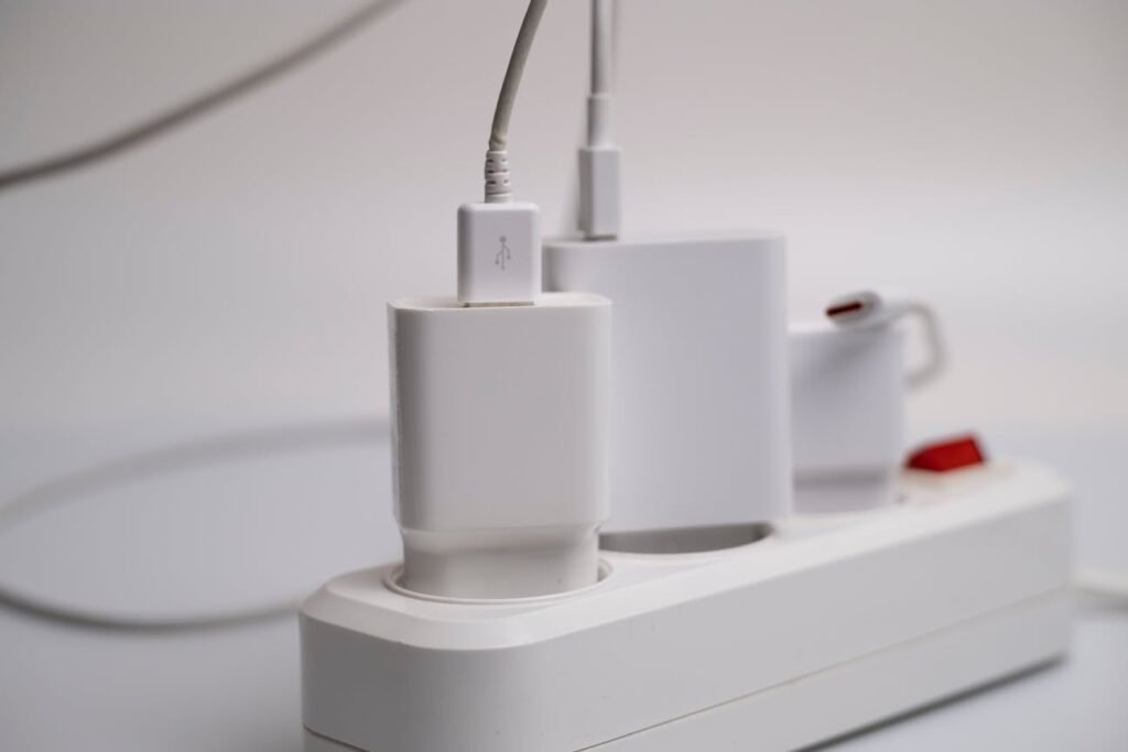 Close-up of a white USB charger plugged into a power strip with multiple charging devices