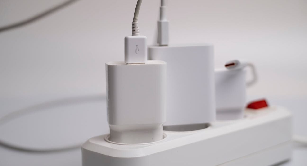 Close-up of a white USB charger plugged into a power strip with multiple charging devices
