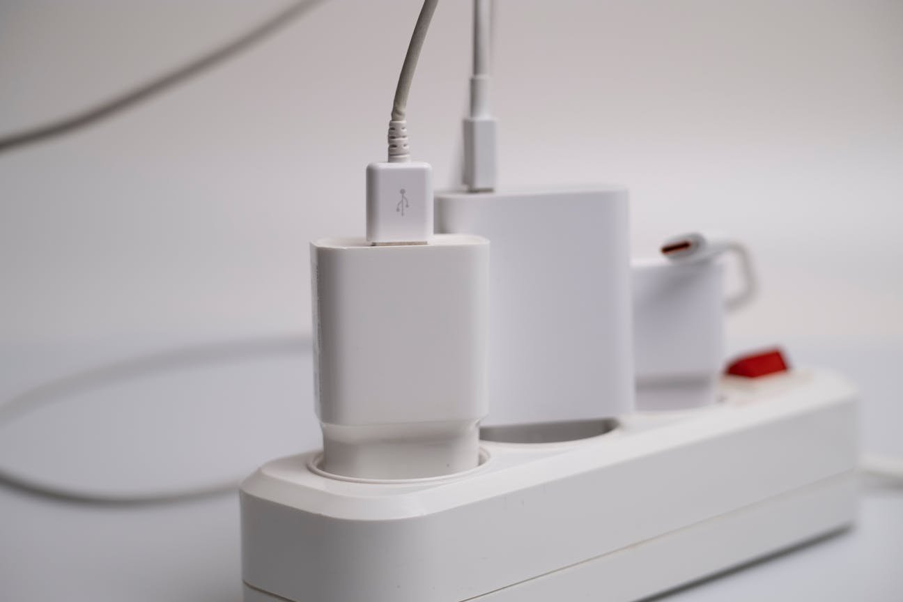 Close-up of a white USB charger plugged into a power strip with multiple charging devices