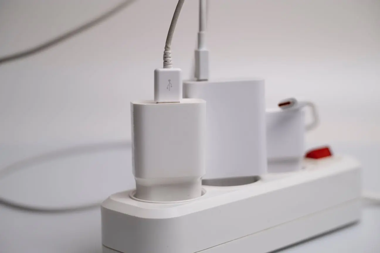 Close-up of a white USB charger plugged into a power strip with multiple charging devices
