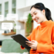 Smiling woman on couch looking at tablet with message bubbles.